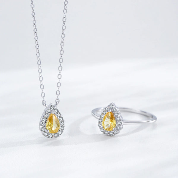 Silver necklace and ring set with yellow gemstones on a white background