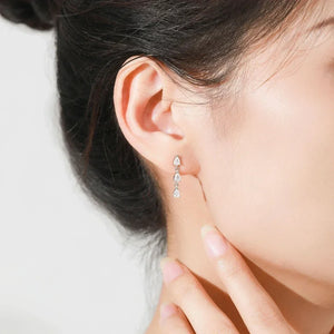 Close-up of a person wearing a teardrop-shaped earring on a light background