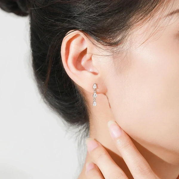 Close-up of a person wearing a teardrop-shaped earring on a light background