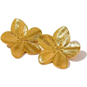 Gold-plated flower stud earrings with textured petals on a light textured surface