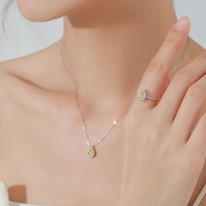 A close-up lifestyle shot of a model wearing a delicate silver chain necklace with a teardrop-shaped yellow gemstone pendant and a matching silver ring on her finger.
