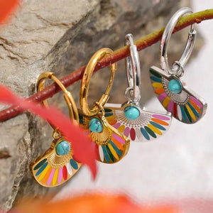 Colorful fan-shaped hoop earrings in gold and silver with turquoise stones on a branch