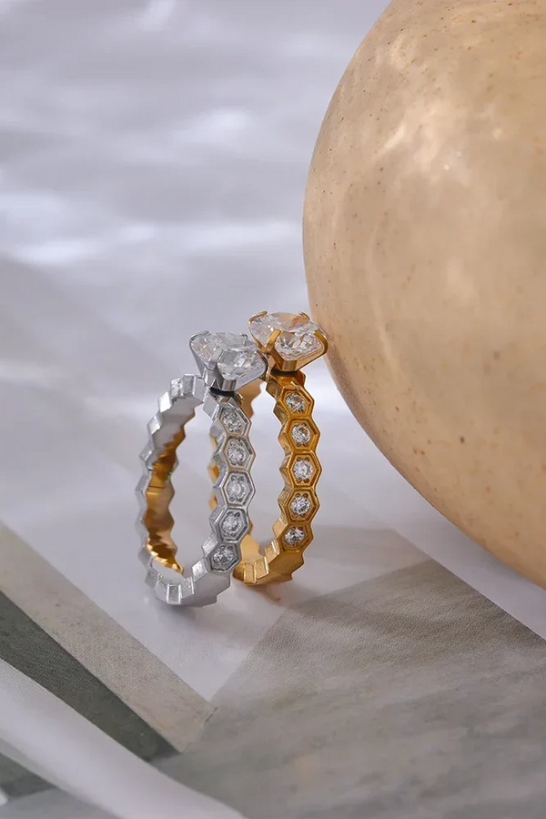 Two gold and silver rings on a marble surface with a stone background