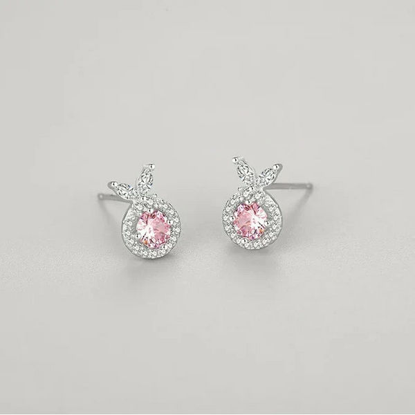 Pair of silver earrings with pink gemstones on a light gray background