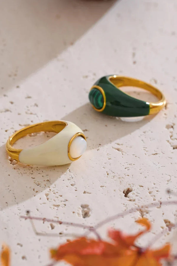 Two rings, one green and one beige, on a textured surface with floral design.