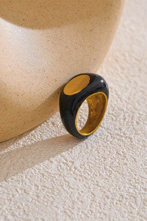Black and gold ring on a textured beige surface