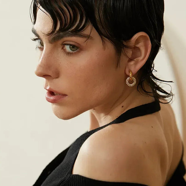Gold-plated hoop earring with crystal accents, worn by woman with short dark hair, elegant everyday jewelry