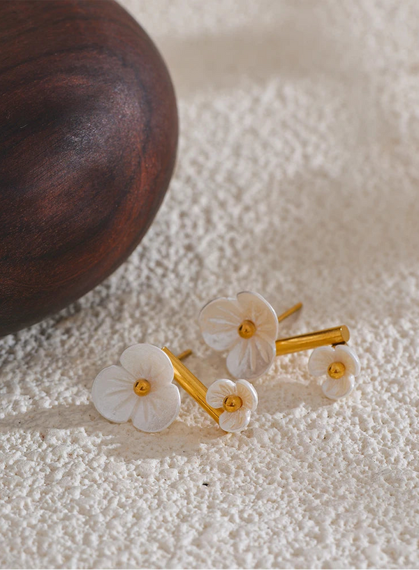 Flower-shaped earrings with gold accents on a textured surface