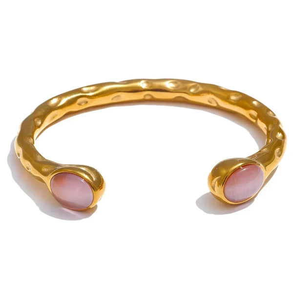 Gold bracelets with colorful stones on a textured surface, branded as Vogue.