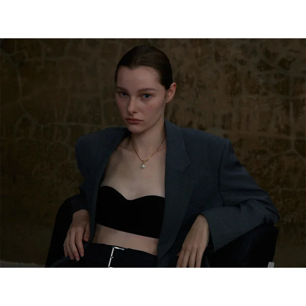 Woman wearing a black blazer over a black top with a textured wall background