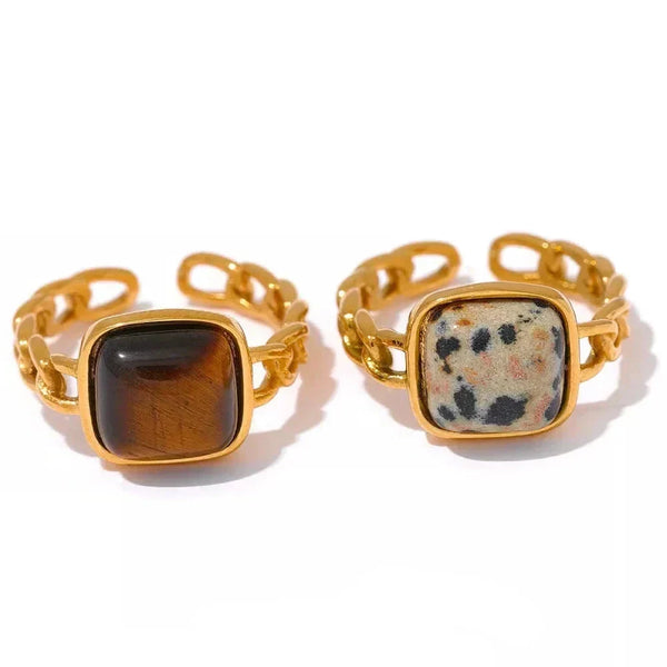 Two gold-rimmed rings with stone inlays on a white background