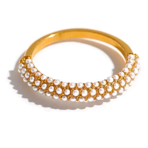 Gold-plated bracelet with rows of small white pearls on a white background