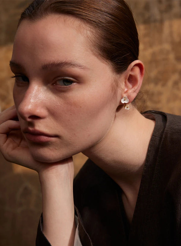 Close-up of a woman wearing earrings with a neutral background