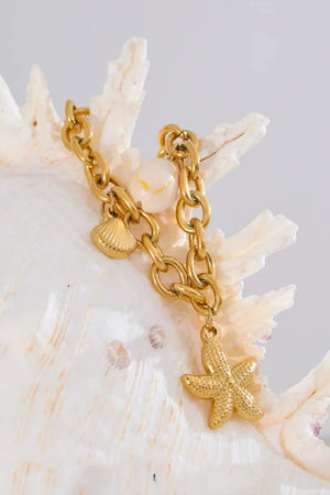 Gold chain bracelet with starfish charm on a seashell background