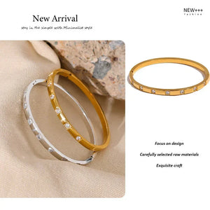 Gold and silver bangle bracelets with cubic zirconia stones on beige fabric
