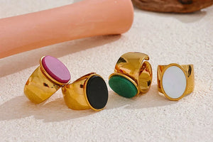 Set of gold-rimmed rings with colorful centers on a textured surface