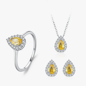 A jewelry set featuring a silver ring, pendant necklace, and matching stud earrings, each with a pear-shaped yellow gemstone surrounded by small clear stones, shown on a clean white background.