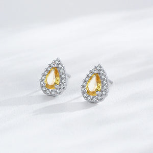Teardrop-shaped earrings with yellow gemstones on a white background