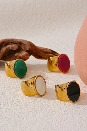 Gold rings with colorful gemstones on a textured surface