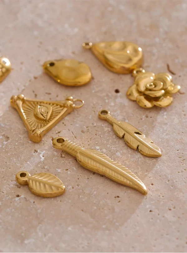 Gold jewelry charms on a textured beige surface