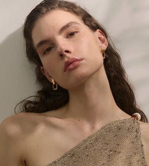 Woman wearing gold hoop earrings against a neutral background