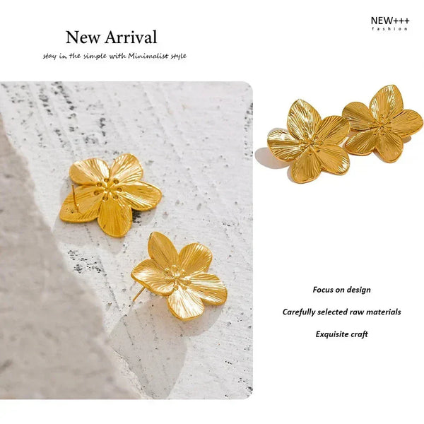 Gold flower-shaped earrings on a textured white surface with 'NEW++' branding.