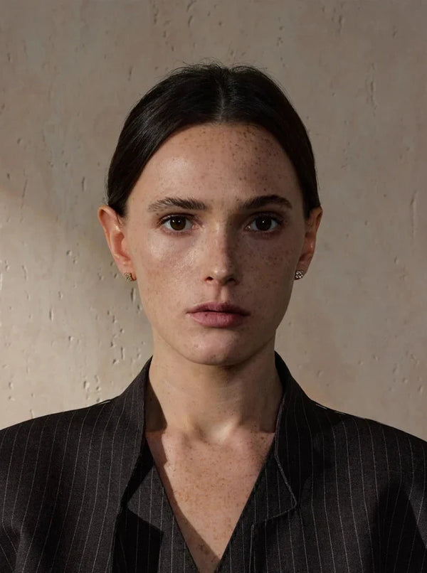 Woman wearing a dark pinstripe shirt against a neutral background
