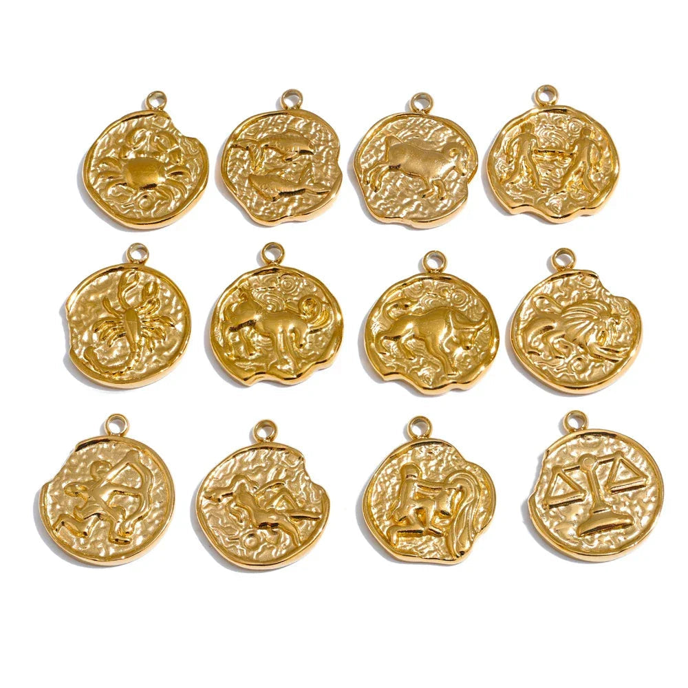 Gold zodiac pendants arranged in a grid on a white background .