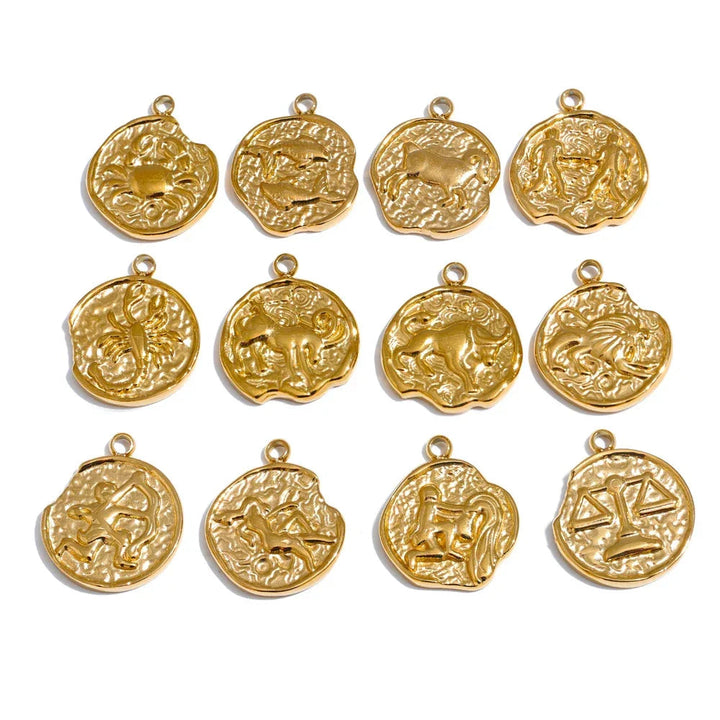 Gold zodiac pendants arranged in a grid on a white background .