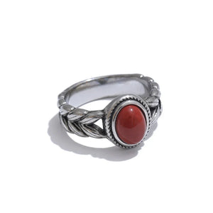 Silver ring with a red stone on a white background.