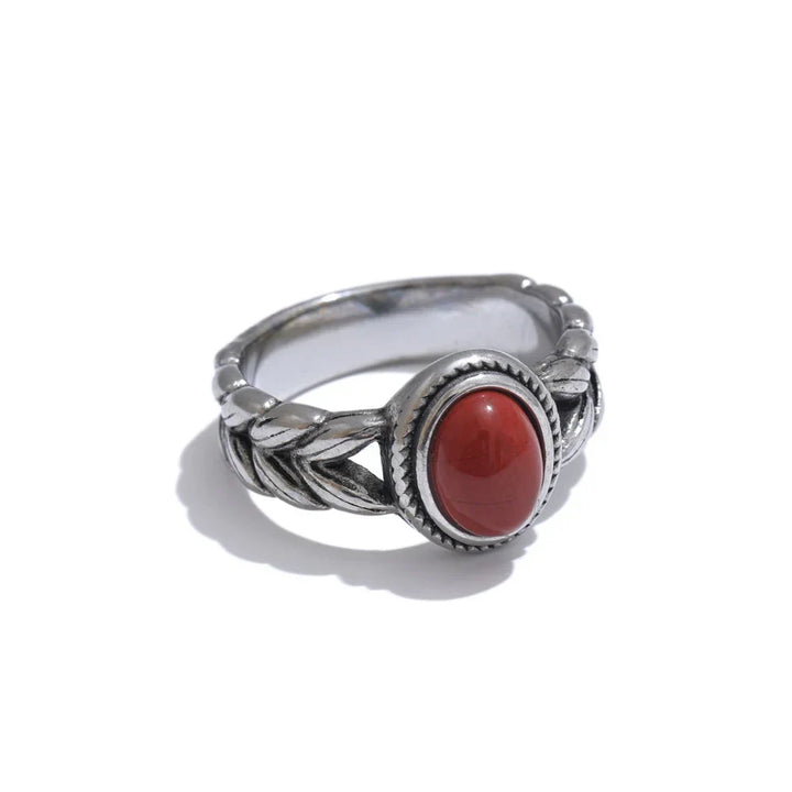 Silver ring with a red stone on a white background.