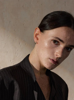 Person wearing a black pinstripe shirt against a beige wall