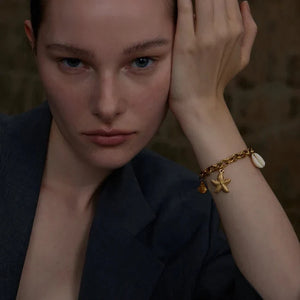 Woman wearing a dark blazer with a starfish bracelet against a blurred background