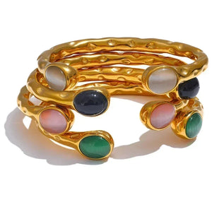 Gold bracelet with multicolored stones on a white background