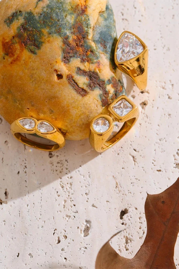 Gold rings with gemstones on a textured stone surface