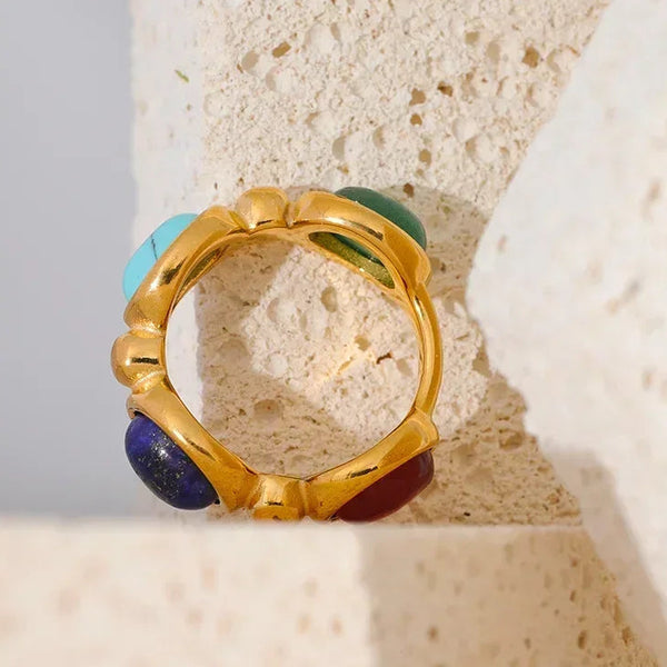 18K gold-plated ring with colorful gemstone cabochons on textured stone background