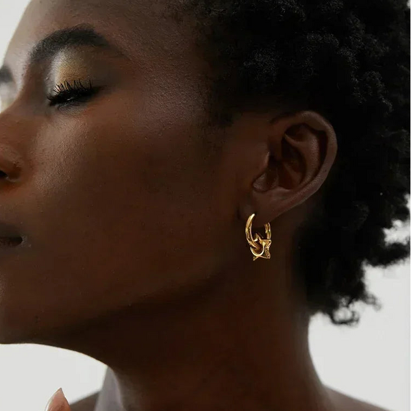 Close-up of a woman Astral Affection Hoops - TM & CO. JEWELS - a gold earring with a neutral background.