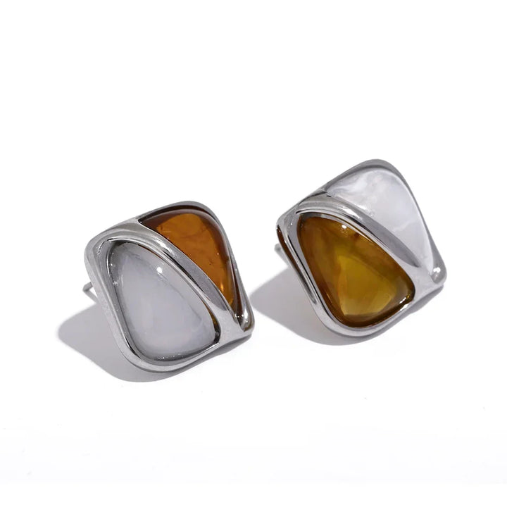 Pair of earrings with brown and clear stones in silver frames on a white background.