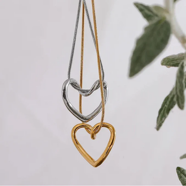 Heart-shaped pendant necklace on a white background with green leaves.