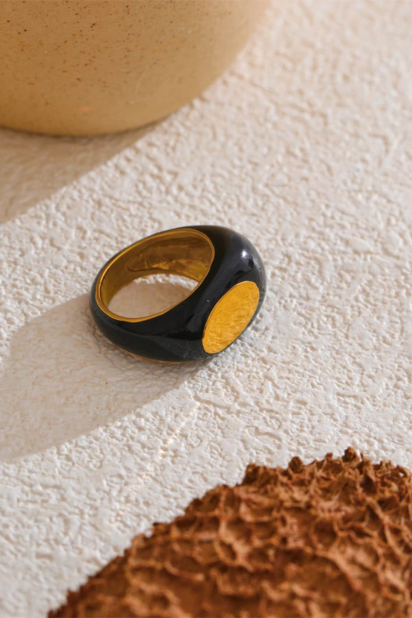 Black ring with gold interior on a textured surface