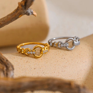 Two rings, one gold and one silver, on a textured surface with a branch.