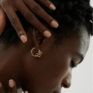 Woman wearing gold-plated hoop earring, close-up jewelry detail