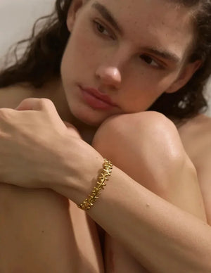 Woman wearing a gold bracelet on a neutral background