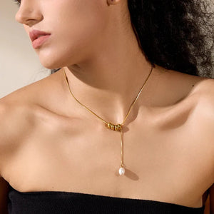 Woman wearing a gold necklace with a pearl pendant