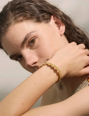 Woman wearing a gold bracelet with a neutral background