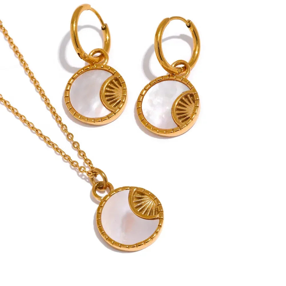 Gold necklace and earrings with white stones on a white background.