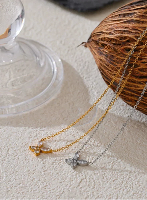 Two necklaces with pendants on a textured surface next to a coconut and glass.