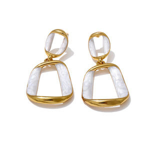 Gold and white earrings on a white background