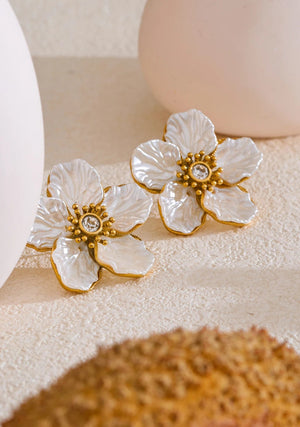 Floral earrings with gold accents on a textured surface