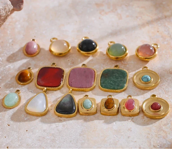 Collection of colorful gemstone pendants on a textured surface